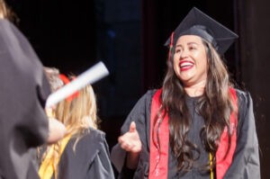 A smiling female graduate of CBD College receives her diploma.