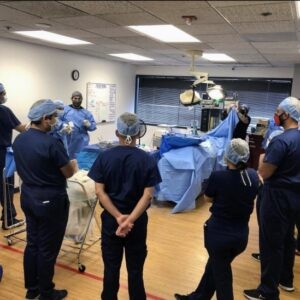 A group of doctors gathers inside the operating room, actively listening to professors as they impart knowledge on surgical techniques and advanced technology. This educational session facilitates the learning and refinement of skills crucial for delivering high-quality surgical care. The exchange of expertise between professors and doctors fosters continuous improvement and innovation in medical practice.