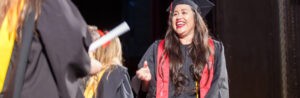 A smiling female graduate of CBD College receives her diploma.