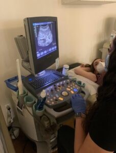 A woman performing an imaging procedure using a medical ultrasound device.