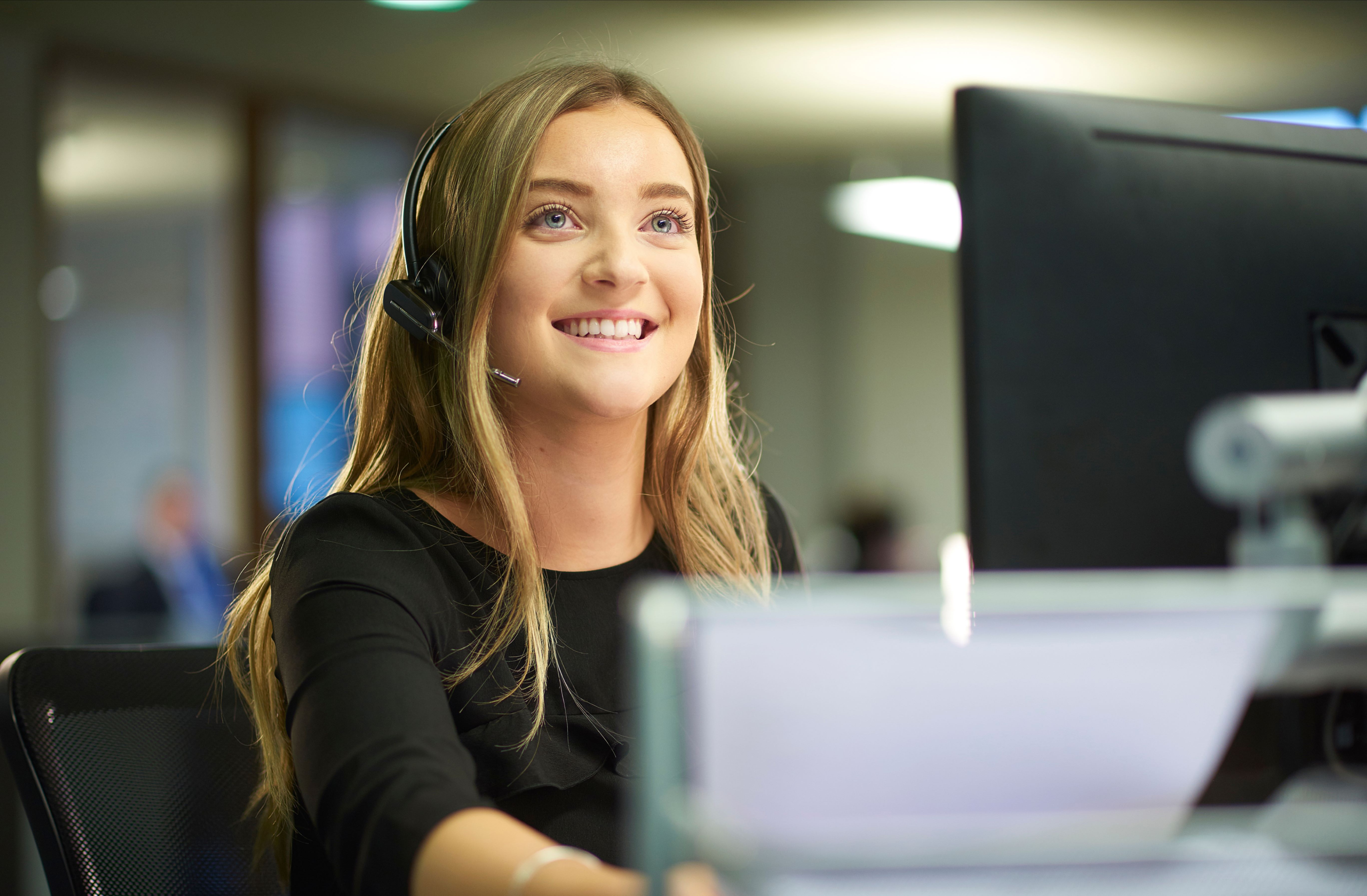 A woman specializing in health information technology transitions to a managerial role in social media. Wearing headphones and holding a microphone, she confidently leads in the digital realm. A computer in front of her signifies her engagement in online platforms, showcasing the dynamic nature of her role.