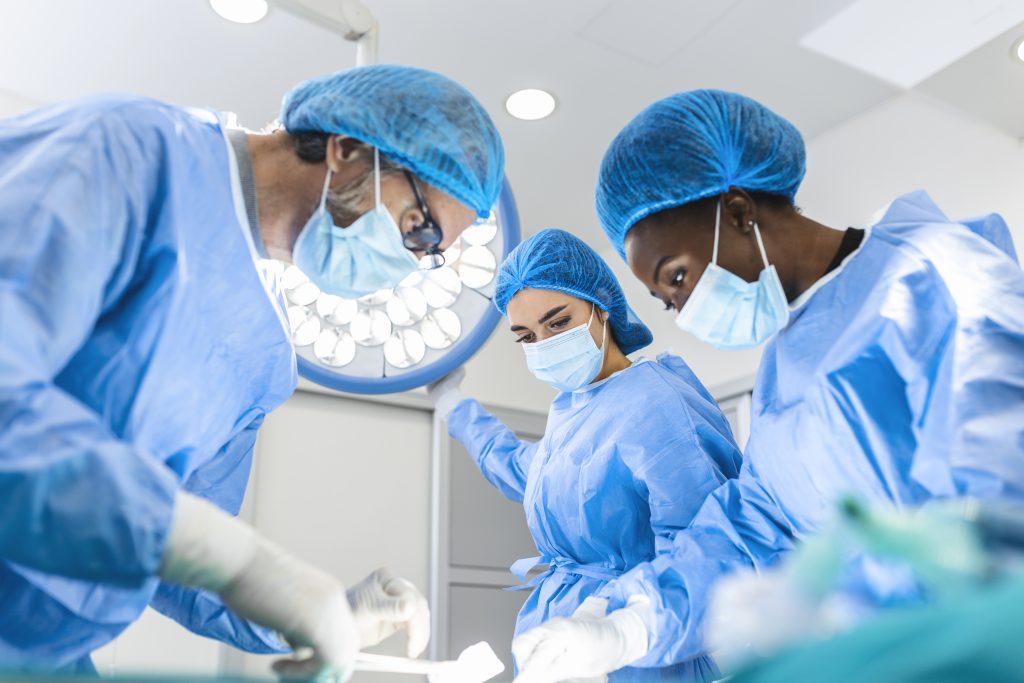 A group of doctors gathers inside the operating room, meticulously preparing for a specialized surgical procedure. Their focused demeanor and coordinated efforts underscore the importance of teamwork and precision in delivering optimal patient care during this critical moment.