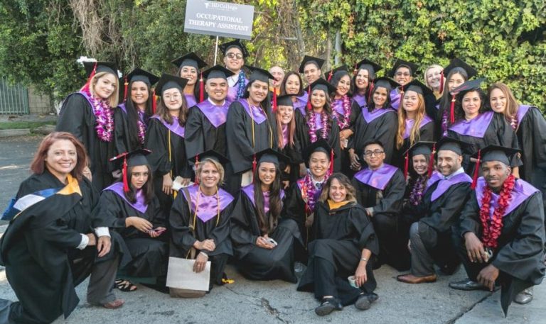 A group of CBD College professors posing for a photo together at the graduation ceremony, smiling proudly and holding their diplomas.