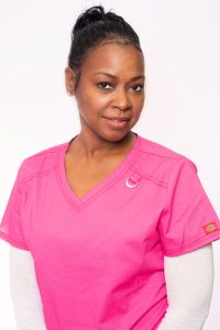 A Female medical assistant wearing a pink blouse.