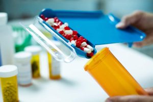 Pharmacy technician filling prescription medication behind the counter in a pharmacy.