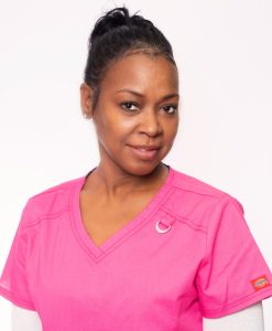 A female medical assistant wearing a pink blouse.