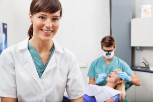 Image of an assistant standing in front of a dental clinic, ready to assist patients with their dental needs.