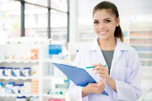 A smiling Asian female pharmacist working in a chemist shop or pharmacy.