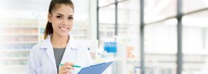 A smiling Asian female pharmacist working in a chemist shop or pharmacy.