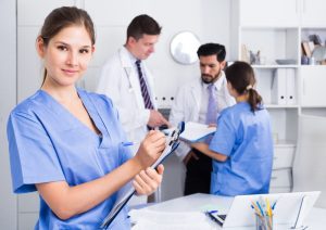 A female doctor assistant standing in a medical office, writing prescriptions.