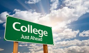 Written sign displaying 'College Just Ahead', indicating the proximity of a college campus or educational institution.