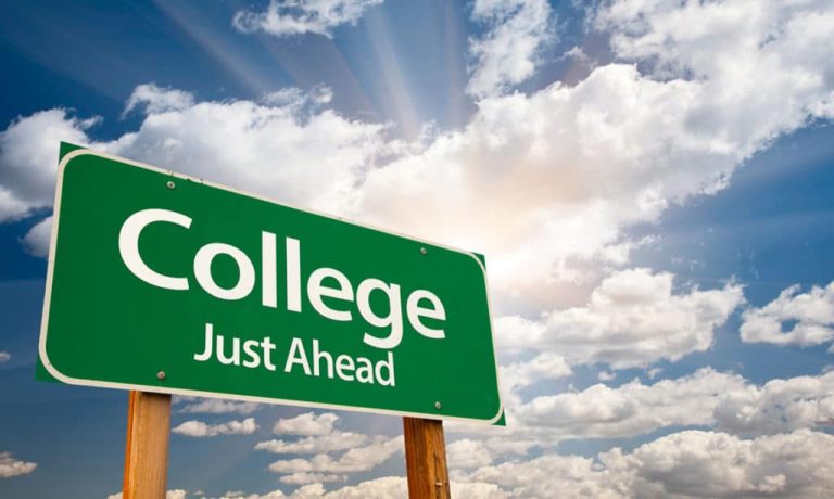 Written sign displaying 'College Just Ahead', indicating the proximity of a college campus or educational institution.