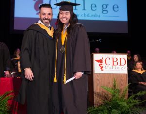 Crystal Lee, RDMS, standing proudly on stage during the graduation ceremony, holding her certificate of completion.