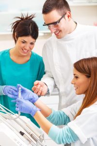 Image of a dental assistant team working together in a dental office, assisting the dentist during procedures, sterilizing equipment, and providing patient care.