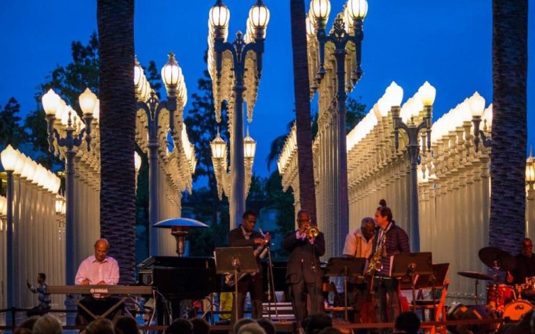 Photograph of a jazz band performing at LACMA (Los Angeles County Museum of Art), with a checklist overlay, symbolizing "Attending Jazz at LACMA" on the summer to-do list.