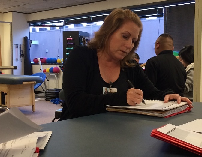 Michelle Theis-Black participating in a hands-on physical therapy training session at CBD College. She is actively engaged in assisting a patient with therapeutic exercises. Her focus and determination demonstrate her commitment to mastering her skills as a future physical therapy assistant.