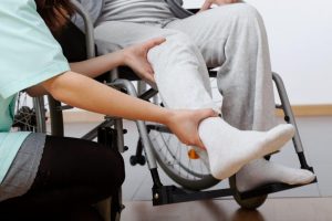 Young physiotherapist exercising with elder disabled person.
