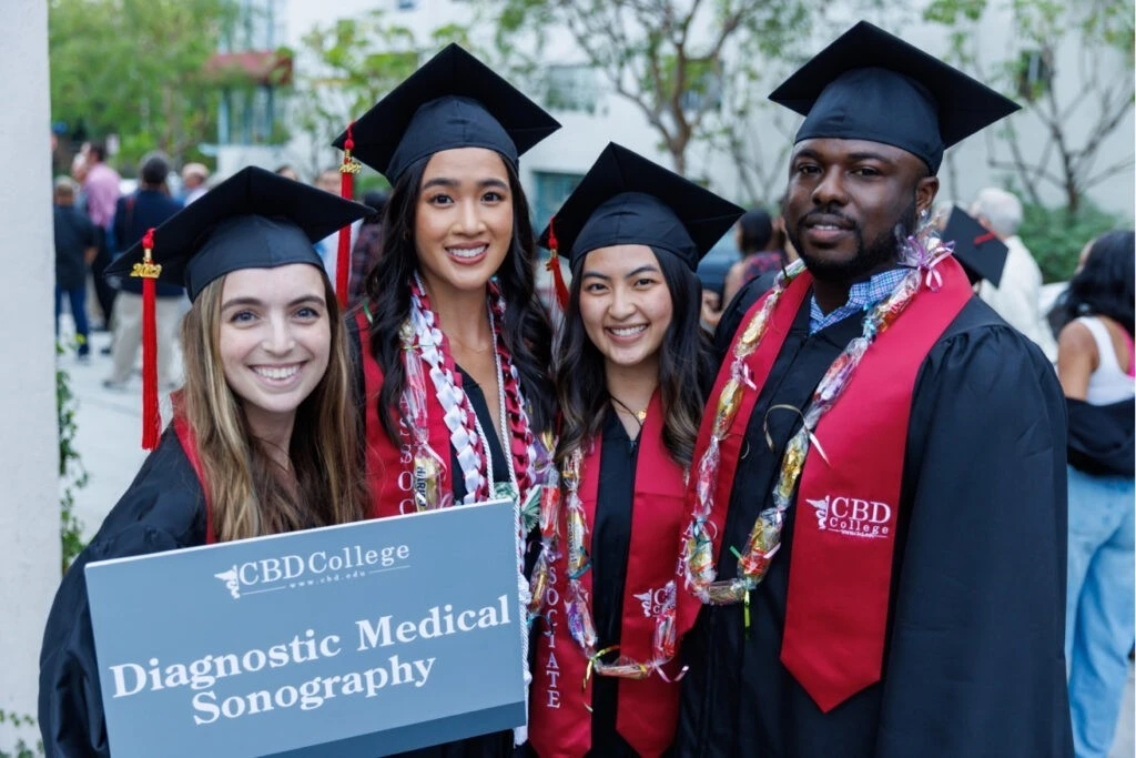 Four successful graduates from CBD College in Diagnostic Medical Sonography celebrating their achievement. Among them are three females and one male, all dressed in graduation robes, symbolizing their academic accomplishment and dedication to the field.