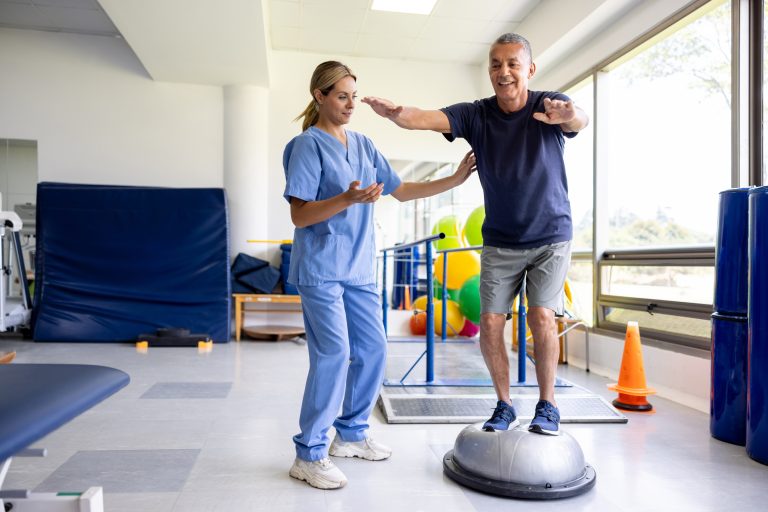 An occupational therapist assistant (OTA) guides a fifty-year-old man through a balance restoration exercise as part of his rehabilitation program. With patience and expertise, the OTA teaches the man techniques and exercises aimed at improving his balance and mobility. This hands-on approach empowers the patient to actively participate in his recovery process, fostering independence and enhancing overall well-being.
