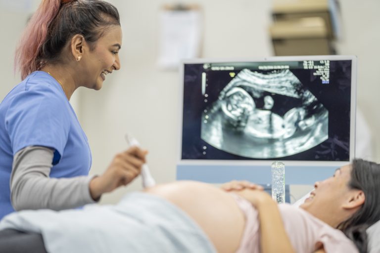 An ultrasound technician performing a scan on a pregnant patient, using ultrasound equipment to monitor the fetus's development.