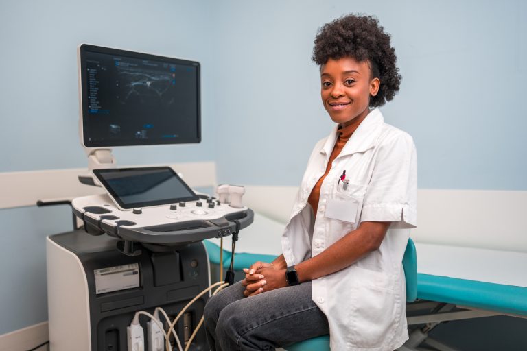 sonographer sitting at ultrasound machine with picture of fetus on screen